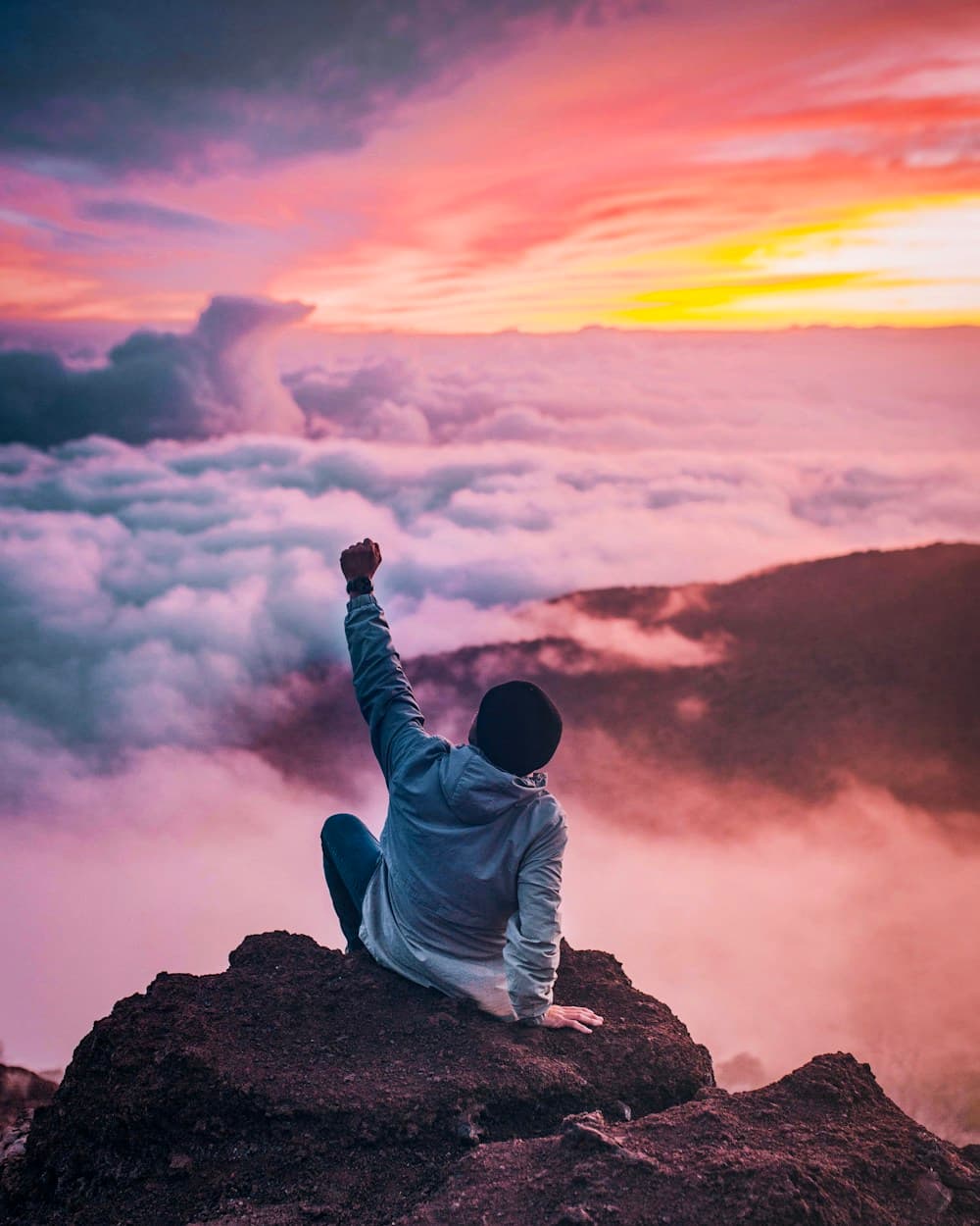 Person standing on mountaintop arms raised — freedom and hope